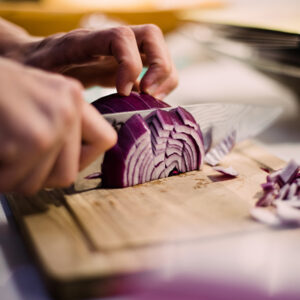 Cutting a red onion with a knife on a cutting board